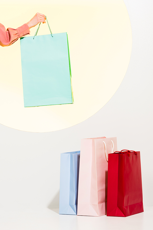 cropped view of girl and colorful shopping bags on white with yellow circle