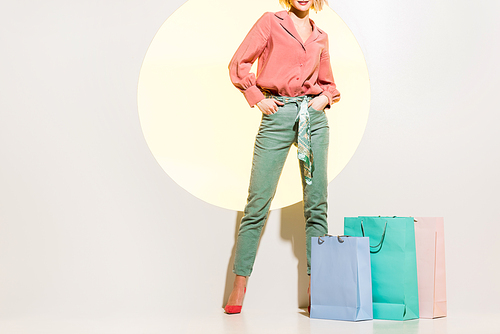 cropped view of stylish girl posing near shopping bags on white with yellow circle
