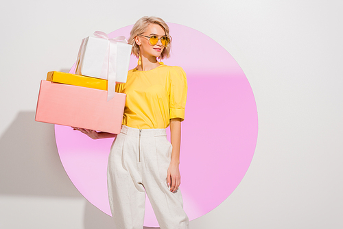 beautiful stylish girl holding gift boxes on white with pink circle and copy space