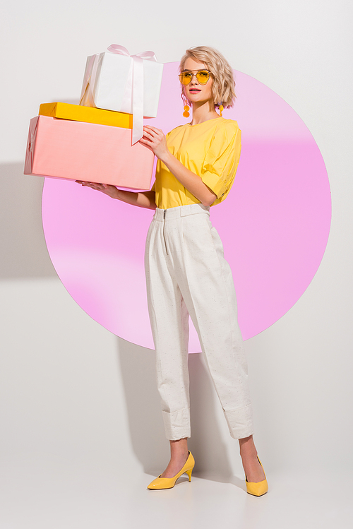 beautiful stylish girl holding gift boxes and  on white with pink circle