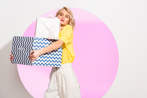 beautiful fashionable girl holding gift boxes on white with pink circle and copy space