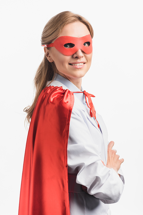 happy nurse in superhero cloak and mask standing with crossed arms isolated on white