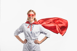 happy nurse in superhero mask and cloak standing with hands on hips isolated on white