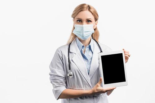 nurse in medical mask and white coat holding digital tablet with blank screen isolated on white