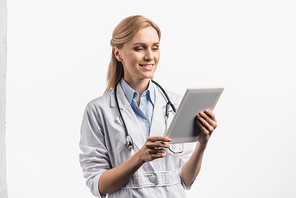 smiling nurse in white coat using digital tablet isolated on white
