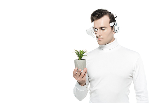 Cyborg man in white clothes, headphones and eye lens looking at potted plant isolated on white