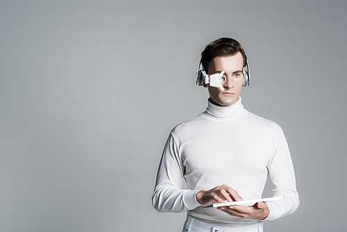 Cyborg man in headphones and eye lens using computer keyboard isolated on grey