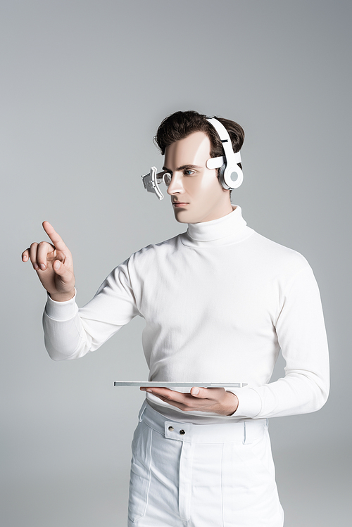 Cyborg in headphones touching something and holding computer keyboard isolated on grey