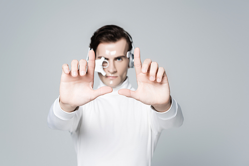 Cyborg man in headphones on blurred background touching something isolated on grey