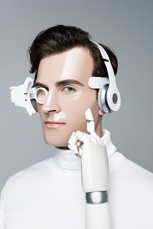 Cyborg in headphones with artificial hand  isolated on grey