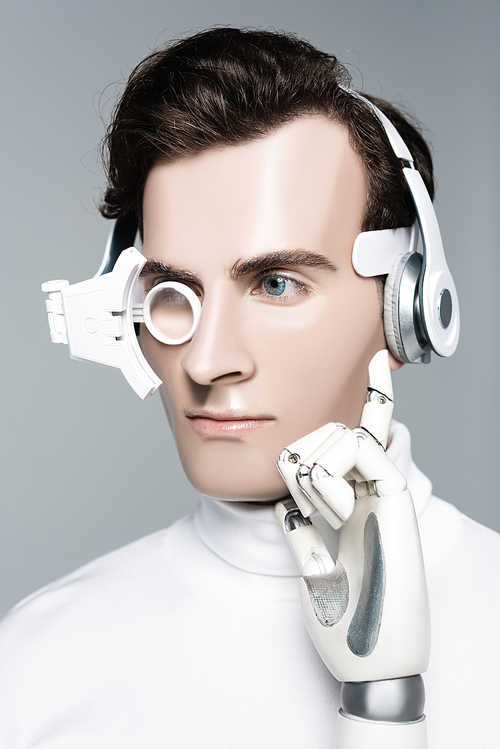 Cyborg man in digital eye lens, headphones and artificial hand looking away isolated on grey