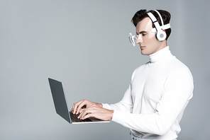 Cyborg in headphones and eye lens using laptop in air isolated on grey