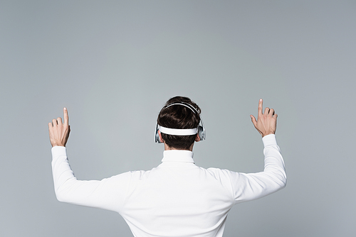 Back view of cyborg in headphones using something isolated on grey