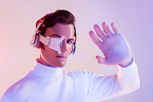 Cyborg in digital eye lens and headphones  near hand on blurred foreground on purple background