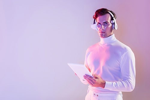 Cyborg in white clothes and headphones holding digital tablet on purple background