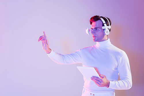 Cyborg in headphones holding digital tablet and using something on purple background