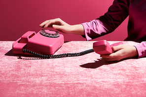 cropped view of woman using retro phone on velour cloth isolated on pink, girlish concept