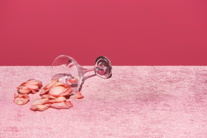 rose petals near glass on velour pink cloth isolated on pink, girlish concept