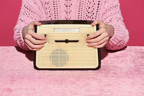 cropped view of woman holding vintage radio on velour cloth isolated on pink, girlish concept