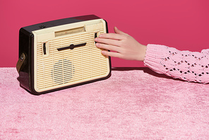 cropped view of woman with vintage radio on velour cloth isolated on pink, girlish concept