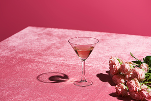 rose wine in glass near bouquet on velour pink cloth isolated on pink, girlish concept