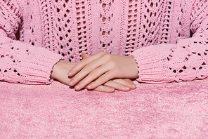 cropped view of woman with clenched hands on velour pink cloth, girlish concept
