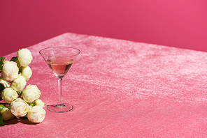 rose wine in glass near bouquet on velour pink cloth isolated on pink, girlish concept