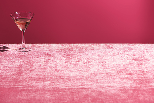 alcohol drink in glass on velour pink cloth isolated on pink, girlish concept