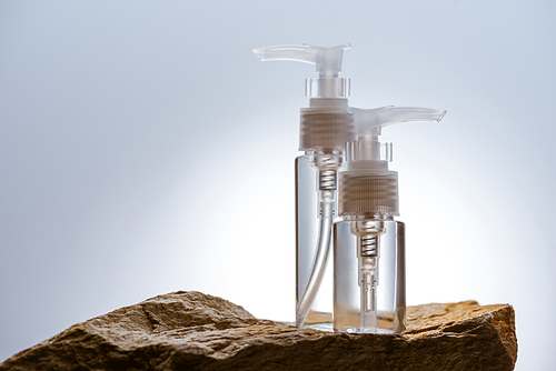 dispenser cosmetic bottles on stone on white background with back light