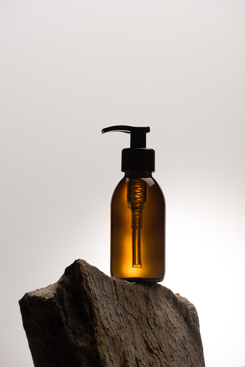 dispenser cosmetic bottle on stone on white background with back light