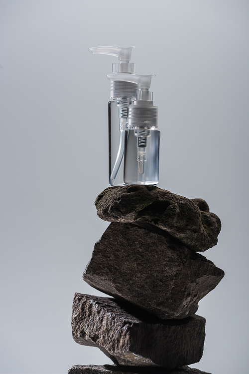 dispenser cosmetic bottles on stones isolated on grey