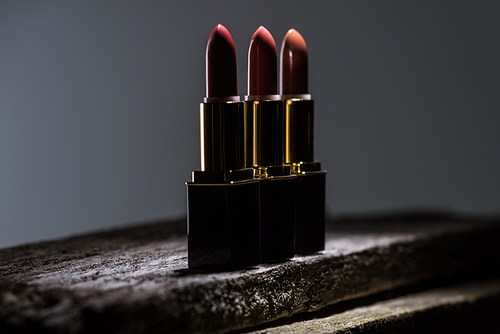 lipsticks arranged in line on stone in dark