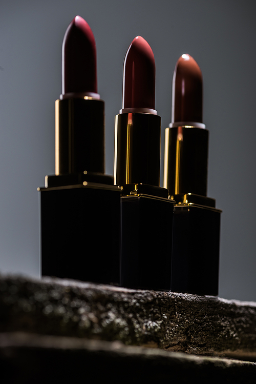 low angle view of lipsticks arranged in line in dark on stone