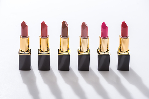 assorted lipsticks in luxury tubes in line on white background
