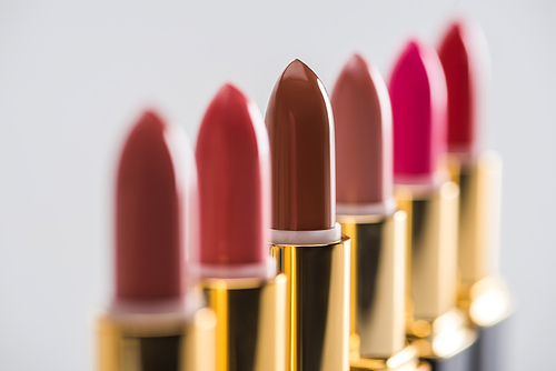 close up view of assorted lipsticks in luxury tubes in line isolated on white