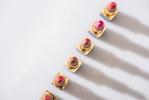 top view of assorted lipsticks in luxury tubes in line on white background