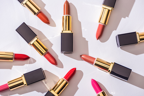 top view of assorted lipsticks in luxury tubes on white background