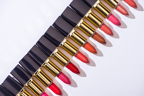 top view of assorted lipsticks in luxury tubes in line on white background