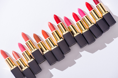 top view of assorted lipsticks in luxury tubes on white background