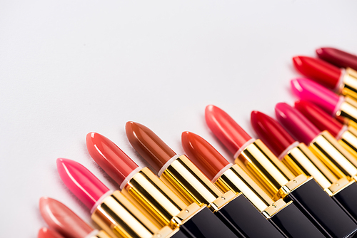 close up view of assorted lipsticks in luxury tubes on white background