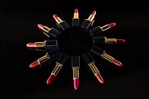 assorted lipsticks in luxury tubes arranged in circle isolated on black