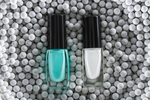 top view of blue and white nail polish in bottles in grey decorative beads