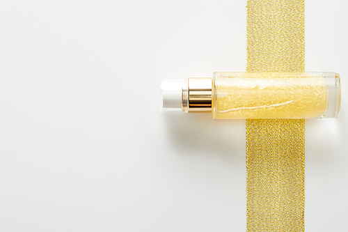 Top view of bottle of cosmetic oil on golden stripe on white background