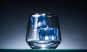 transparent glass with ice cubes in dark with blue back light