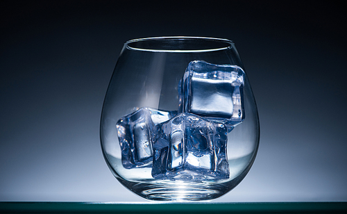 transparent glass with ice cubes in dark with blue back light