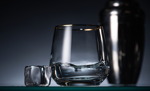selective focus of transparent glass with vodka near ice in dark with back light and shaker
