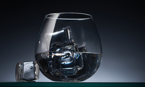 transparent glass with ice cubes and vodka in dark with back light
