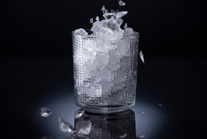 faceted glass with smashed ice on black background