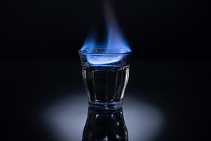 transparent glass with burning liquid on black background