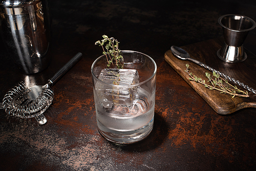 transparent glass with herb, ice cube and vodka on weathered surface